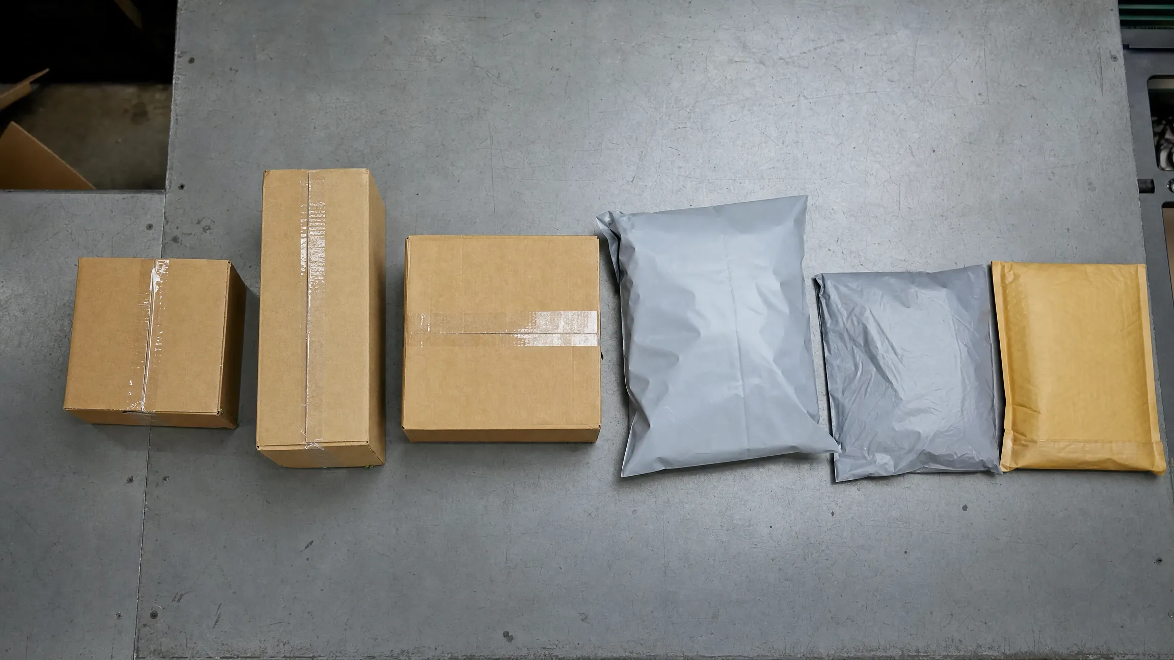 出货台上并排摆放的六种不同规格包装：纸箱、扁盒与灰色快递袋